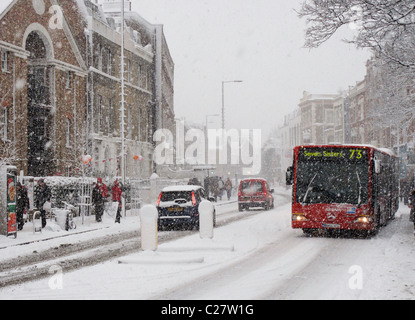 Bus e auto guidando attraverso la neve. Church Street, Stoke Newington, Londra. Foto Stock