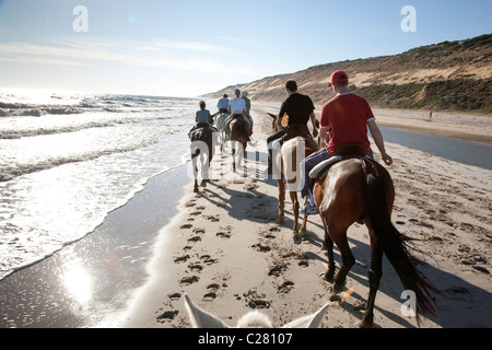 La gente a cavallo sulla spiaggia di Matalascañas, parco nazionale di Donana, Andalusia, Spagna Foto Stock