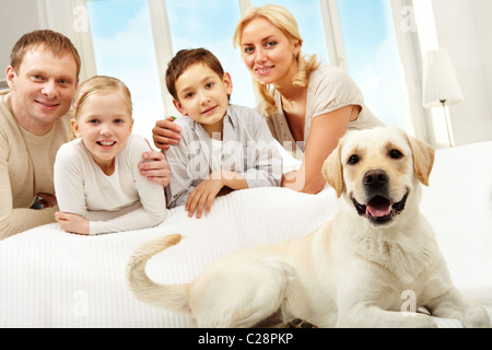 Un grosso cane sdraiato sul divano, una famiglia di quattro persone in piedi dietro Foto Stock