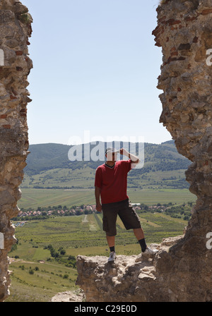 Uomo a scrutare l'orizzonte da una fortezza rocciosa rovina in una zona montuosa. Foto Stock