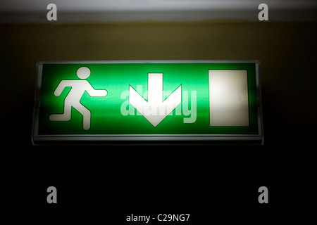 Uscita di emergenza segno verde brillante nel buio Foto Stock