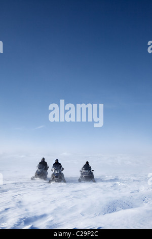 Tre motoslitte in un paesaggio invernale con lavori di soffiaggio della neve Foto Stock