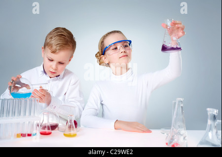 Un ragazzino versando il liquido in un tubo e il suo assistente lo scuotimento di un pallone Foto Stock