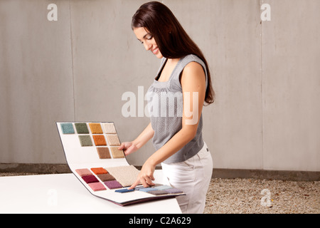Una femmina di interior architetto o designer guardando rug campioni da un catalogo Foto Stock
