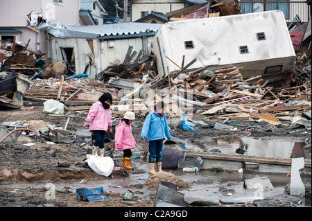 Bambini giapponesi guardare le barche da pesca, le auto e le case sono state completamente distrutte dopo un 9.0 Mw terremoto tsunami Foto Stock