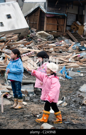 Ragazze giapponesi guardare le barche dei pescatori, le auto e le case sono state completamente distrutte dopo un 9.0 Mw terremoto provocò un maremoto Foto Stock