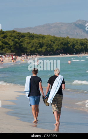 I turisti a passeggiare lungo la spiaggia di Puerto de Alcudia, Mallorca, Spagna Foto Stock