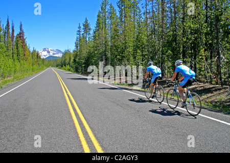 I ciclisti che viaggiano verso le sorelle montagna sopra la cascata Lakes National Scenic Byway Oregon Foto Stock