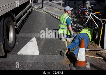 I contraenti sui lavori in corso nella strada che passa vicino a HGV camion (carrello) nel centro di Londra. Foto Stock