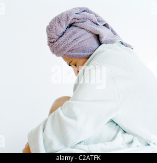 Donna rilassante in accappatoio con asciugamano sulla testa Foto Stock