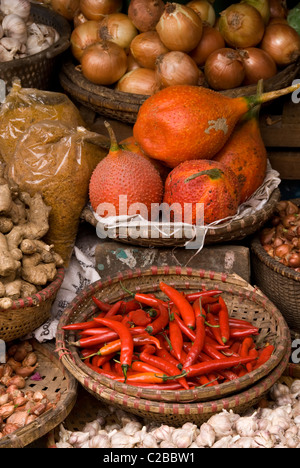 Cestini di frutta gac, peperoncino, cipolle, scalogni, zenzero e aglio in un mercato in Hanoi Old Quarter, Viet Nam Foto Stock