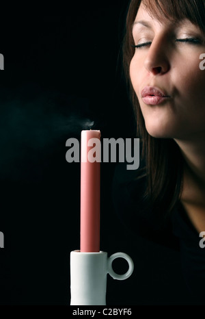 Una giovane donna soffiando fuori una candela Foto Stock