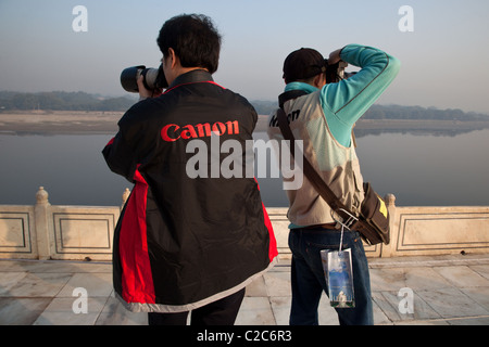 I turisti cinesi indossando Canon e Nikon canottiere scattare foto fiume Yamuna dal Taj Mahal di Agra, India. Foto Stock