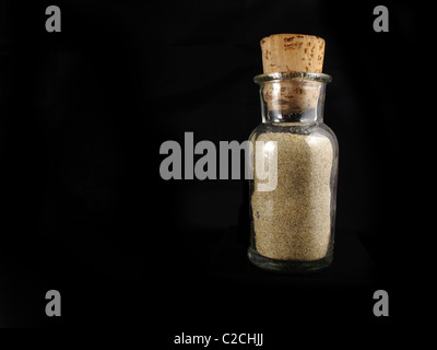 Trasparente bottiglia di vetro con sabbia e un fondo marrone Foto Stock