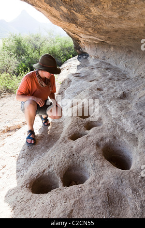 Donna con fondamento preistorici mortaio fori a Cuevas Amarillas rock shelter Big Bend Ranch State Park Texas USA Foto Stock