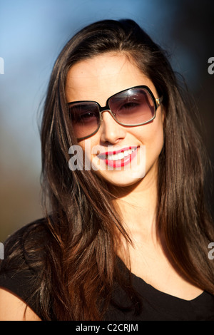 Ritratto di una giovane e bella donna sorridente e indossando occhiali da sole, London, England, Regno Unito Foto Stock