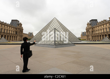 Uomo di scattare una foto con la fotocamera di un cellulare in del Louvre Napoleone cortile con I.M. Pei la piramide in vetro. Foto Stock