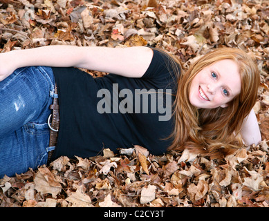 Bella ragazza adolescente giacente in caduta foglie. Foto Stock