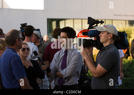Nightly News Cameraman tenendo una videocamera mentre un reporter conduce un colloquio. Foto Stock