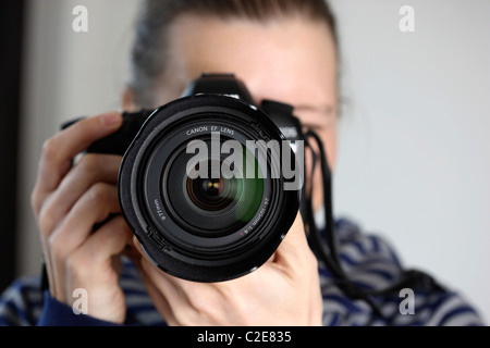 Persona, femmina, guarda attraverso il mirino di una fotocamera reflex digitale. Foto Stock
