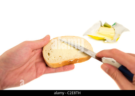 Diffusione a mano il burro sulla fetta di pane,isolato su bianco Foto Stock