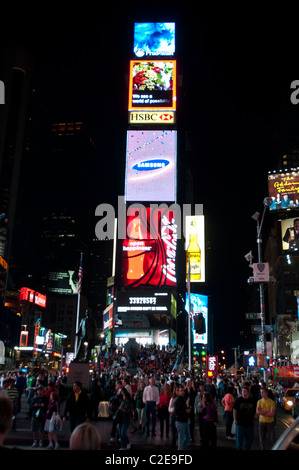 Scena notturna con un sacco di turista di fronte due Times Square tabellone elettronico edificio, Manhattan, New York City, Stati Uniti d'America Foto Stock