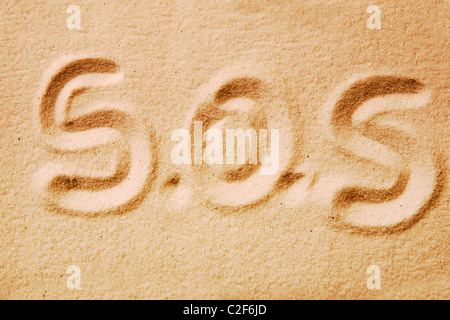 S.O.S. scritto in sabbia dorata - messaggio di emergenza Foto Stock