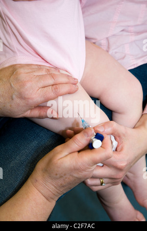 MMR immunizzazione etc / inoculazione / jab / da una siringa in un anno di età / 12 13 dodici tredici mese del bambino / coscia della gamba. Foto Stock