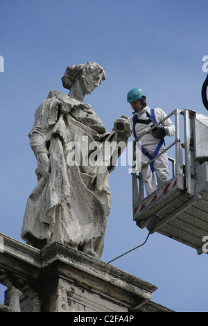 Lavoratori riparando le statue sulla sommità del colonnato di Piazza San Pietro a Roma Foto Stock