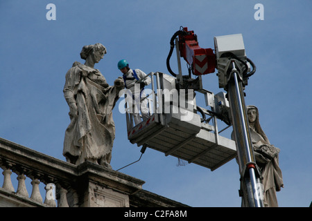 Lavoratori riparando le statue sulla sommità del colonnato di Piazza San Pietro a Roma Foto Stock