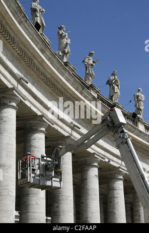 Lavoratori riparando le statue sulla sommità del colonnato di Piazza San Pietro a Roma Foto Stock