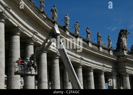 Lavoratori riparando le statue sulla sommità del colonnato di Piazza San Pietro a Roma Foto Stock