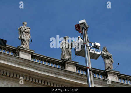 Lavoratori riparando le statue sulla sommità del colonnato di Piazza San Pietro a Roma Foto Stock