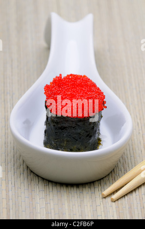 Vivacemente colorate di rosso Tobiko Flying Fish Roe (uova) su un rotolo di sushi Foto Stock