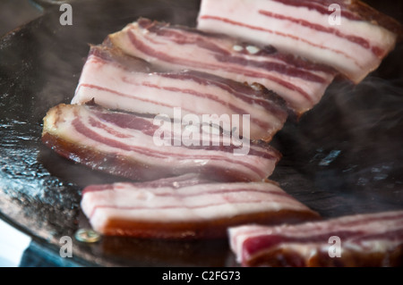 Rosso gustose fette di pancetta grigliare su una piastra. Foto Stock