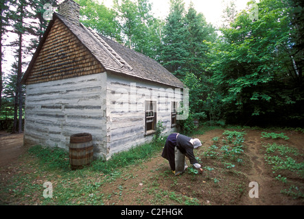 1, una donna canadese, diserbo giardino, indossando il costume, Acadian Historical Village, vicino alla città di Caraquet, New Brunswick Provincia, Canada Foto Stock