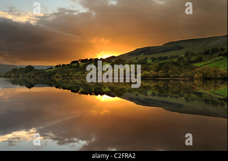 Un fuoco di autunno tramonto riflesso in acque ancora di Semer acqua, North Yorkshire. Foto Stock