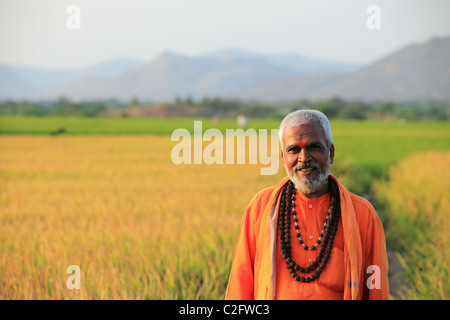 Uomo indiano in sadhu vestito a piedi in un campo di risone di Andhra Pradesh in India del Sud Foto Stock