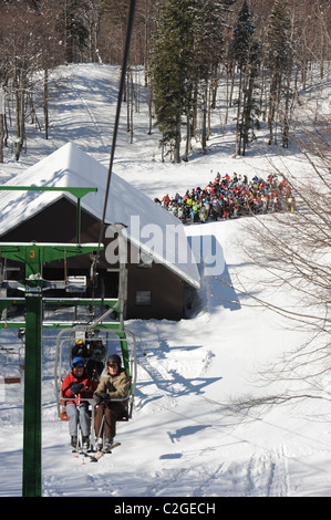 Gli sciatori in coda per una seggiovia a Vogel Ski Center sul Sija - Zadnji Vogel piste del Parco Nazionale del Triglav di Sloven Foto Stock