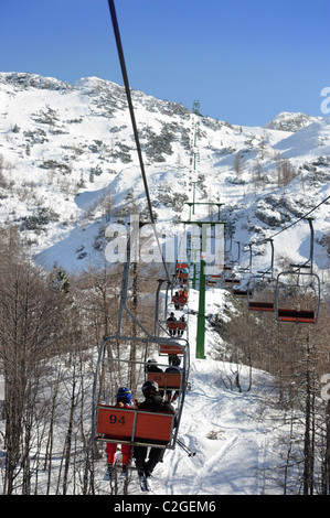 Gli sciatori in seggiovia al Vogel Ski Center dalla base del Sija - Zadnji Vogel piste del Parco Nazionale del Triglav di Slo Foto Stock