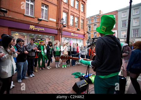 Il giorno di San Patrizio festaioli di Grafton Street, Dublin, Irlanda guardando una banda musicista di strada e la riproduzione di musica Foto Stock