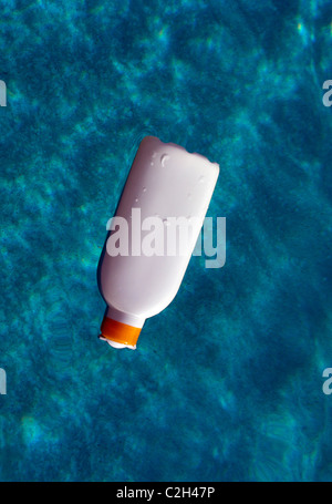 Bottiglia di schermo solare galleggiante in acqua Foto Stock