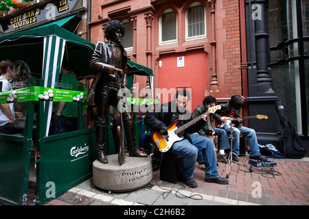 I lettori di musica accanto alla statua del musicista Phil Lynott dalla band Thin Lizzy. Il giorno di San Patrizio a Dublino Irlanda Foto Stock