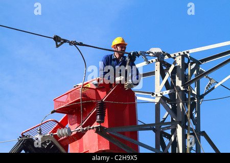 Elettricista lavorando sulla sommità di una torre Foto Stock