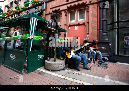 I lettori di musica accanto alla statua del musicista Phil Lynott dalla band Thin Lizzy. Il giorno di San Patrizio a Dublino Irlanda Foto Stock