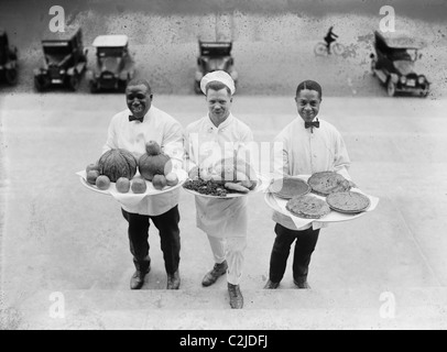 Tre chef stand sul fondo di una linea di passi e tenere premuto il tasto up ringraziamento vassoi di torte di mele e una Turchia Foto Stock