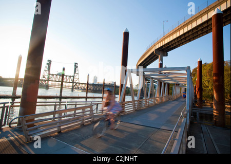 Ciclista sulla vera Katz Eastbank Esplanade passerella galleggiante sul fiume Willamette, acciaio vista Ponte di Portland, Oregon, Stati Uniti d'America Foto Stock