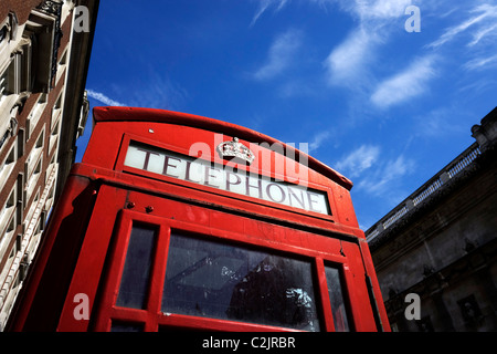 Bassa angolazione di un telefono rosso nella casella e cielo blu in London, England, Regno Unito Foto Stock