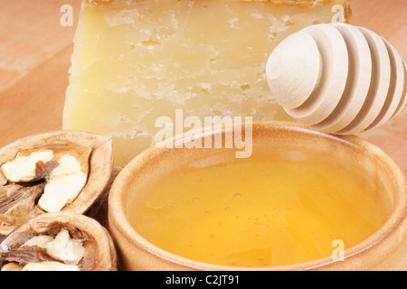 Una piccola tazza di ceramica piena di miele pronto per essere servito con il formaggio pecorino e noci Foto Stock