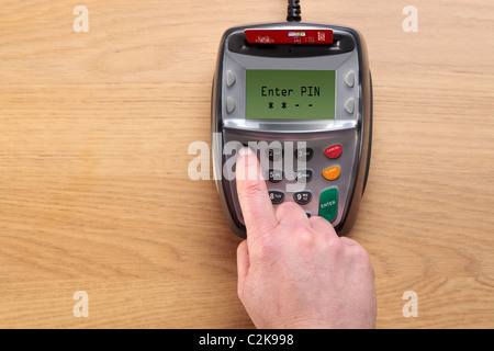 Foto di una mano womans digitando il suo numero in un chip e pin terminale carte di credito, la carta nella macchina è un mock up. Foto Stock